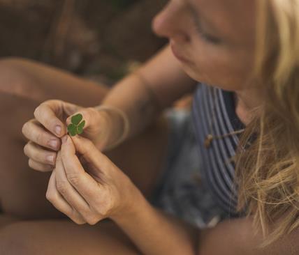 A seated woman is holding a four-leaves clove