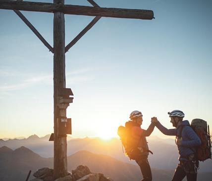 Zwei Bergsteiger auf einem Gipfel bei Sonnenaufgang