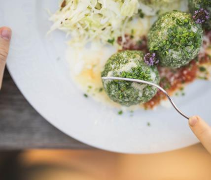 Someone is dividing a spinach dumpling with a fork