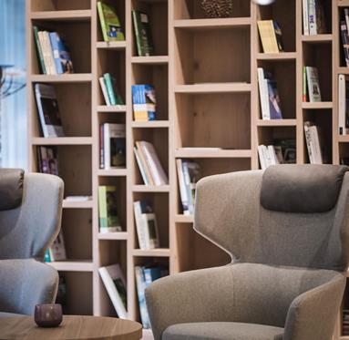 Una grande libreria, un tavolino rotondo e due poltrone nel nuovo pianoterra