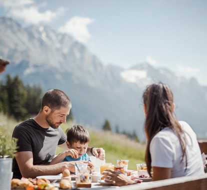 Una famiglia fa colazione all'aperto con vista sulle montagne
