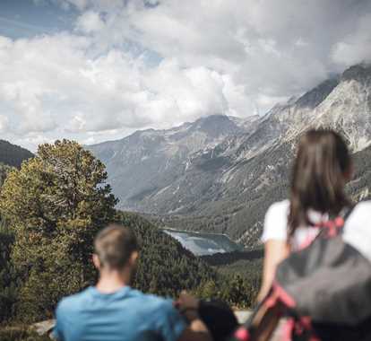 Zwei Wanderer genießen die Aussicht auf die Berge und einen See
